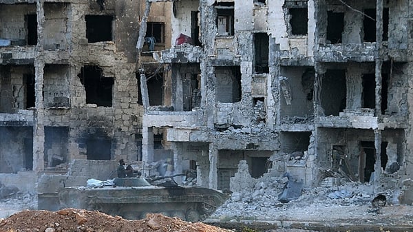 Syrian pro-government forces drive an infantry fighting vehicle past heavily damaged buildings in Aleppo's 1070 district