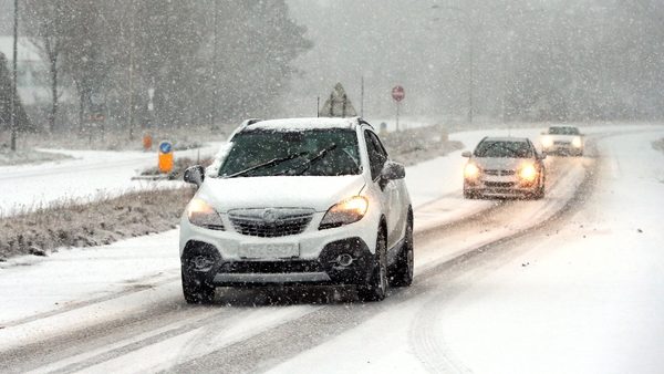 Cars drive through snow on the A26 in Ballymena, Co Antrim this morning
