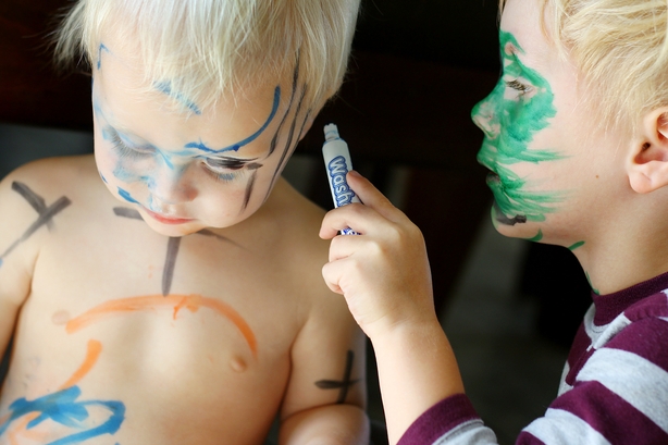 Young Child Coloring Baby Brother's Face