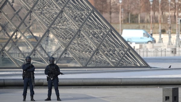 Police officers stand guard near the Pyramid of Le Louvre Museum, close to the Carrousel du Louvre