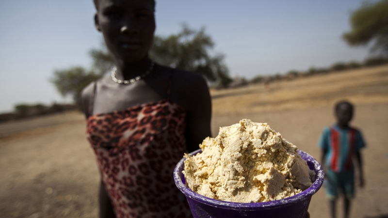 A woman holds out a bowl of partially boiled maize in South Sudan's Unity State