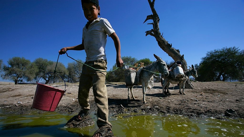 Local people collecting water from a muddy waterhole in Mexico