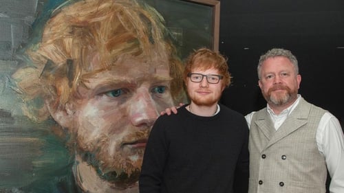 Ed Sheeran posing with his giant portrait alongside artist Colin Davidson