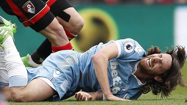 Joe Allen winces in pain after a tackle from Harry Arter
