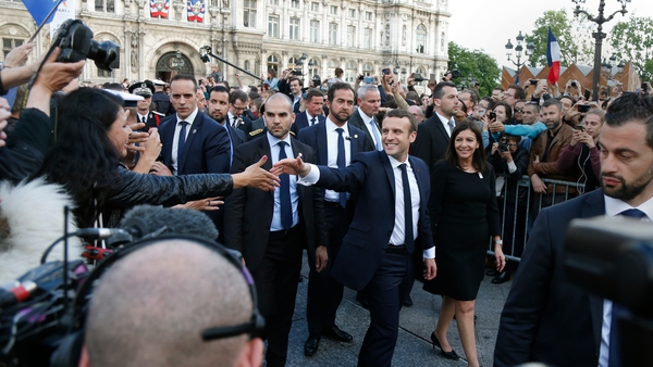 French President Emmanuel Macron (centre) greets the crowds as he walks with Paris Mayor Anne Hidalgo after the ceremony
