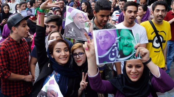Supporters of Iranian president Hassan Rouhani hold pictures of him as they celebrate his victory on the streets of Tehran