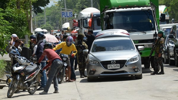 Philippine policemen check the belongings of residents fleeing Marawi