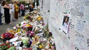 People look over messages from local residents on a wall of condolence close to Grenfell Tower
