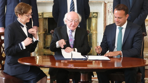 President Michael D Higgins and Taoiseach Leo Varadkar sign the documents to seal Máire Whelan's appointment to the Court of Appeal