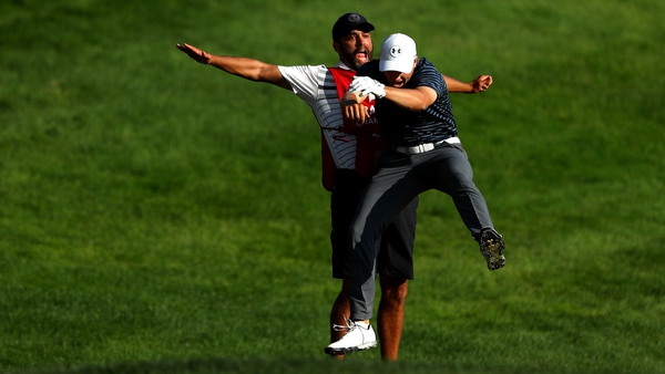 Spieth celebrates with caddie Michael Greller after chipping in for birdie from a bunker on the 18th green to win the Travelers Championship in a playoff against Daniel Berger
