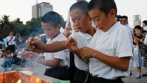 Children light incense sticks to offer prayers at the Hiroshima Peace Memorial Park