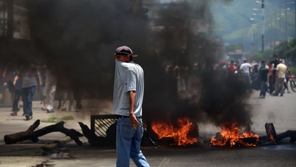 An anti-government activist stands near a burning barricade in Venezuela's third city, Valencia