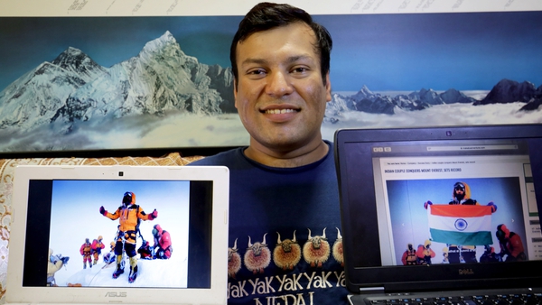 Climber Satyarup Sidhantha holds a photograph in his right hand that shows him on Mount Everest, and in the left hand, an altered version of the photo used by the Indian couple