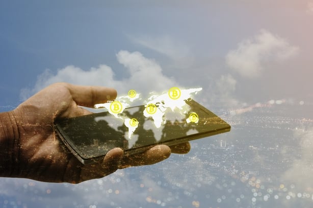 Hand holding smartphone with bitcoin on 3d world map, virtual currency concept
