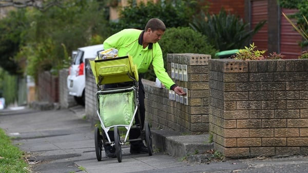 A postman delivers mail into boxes outside a residential building in Sydney as a contentious postal survey on same-sex marriage gets under way