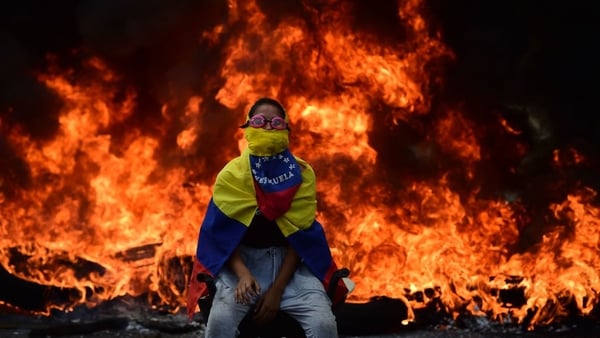 A Venezuelan opposition activist in front of a burning barricade during a demonstration against President Maduro