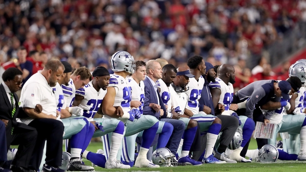The Cowboys kneel and link arms before the game