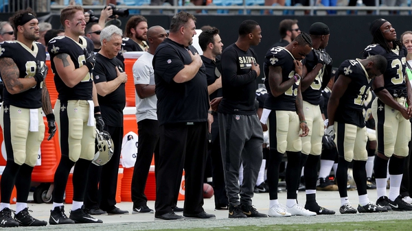 The New Orleans Saints stand during the National Anthem before their game against the Carolina Panthers