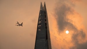 A plane flies past the Shard in central London, as the sky takes on an unusual orange colour caused by Storm Ophelia