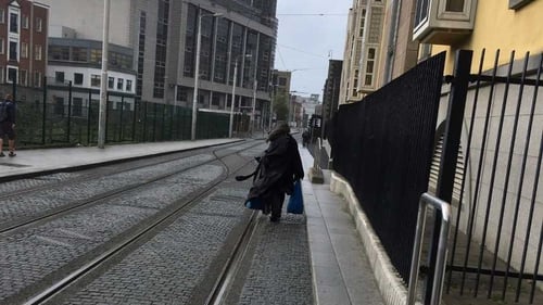 A homeless man who sleeps rough in Dublin walking along the Luas line near the Four Courts