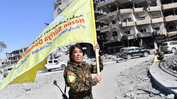A Syrian Democratic Forces commander waves her group's flag in Al-Naim square in Raqqa