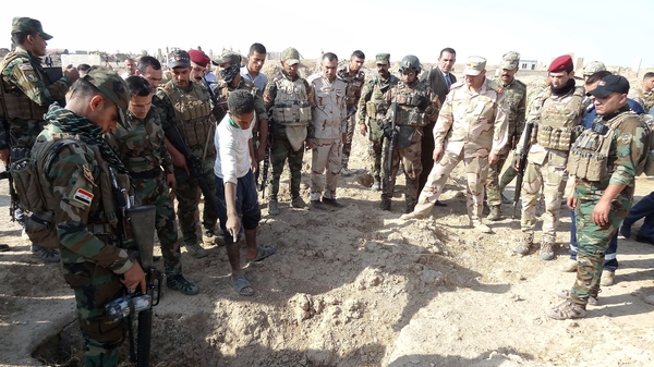 Iraqi forces search the site of a suspected mass grave containing the remains of victims of the Islamic State group
