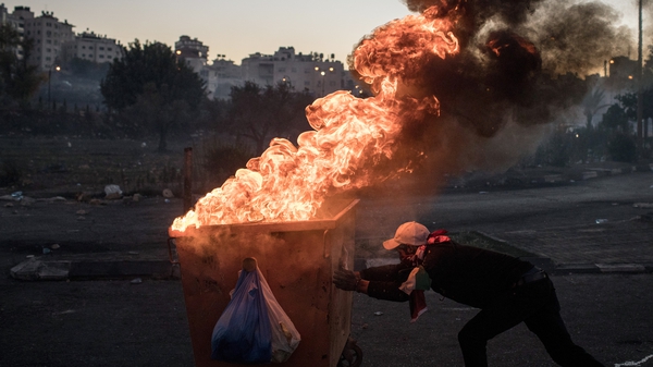 A burning dumpster is pushed down a street to make a barricade during clashes near an Israeli checkpoint in Ramallah, West Bank