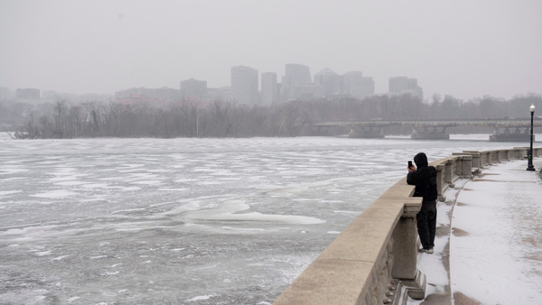 A man photographs the frozen Potomac River during a snow storm in Washington, DC