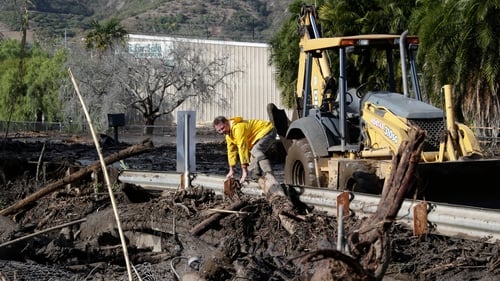 Firefighters and local officials work amid in mud after heavy rains