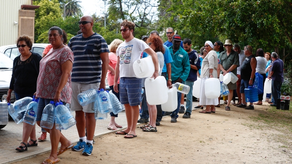 Residents queue for water at a mountain spring collection point