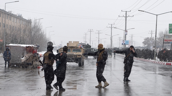 Afghan security personnel detain a suspect at the site of an attack near a military academy base in Kabul
