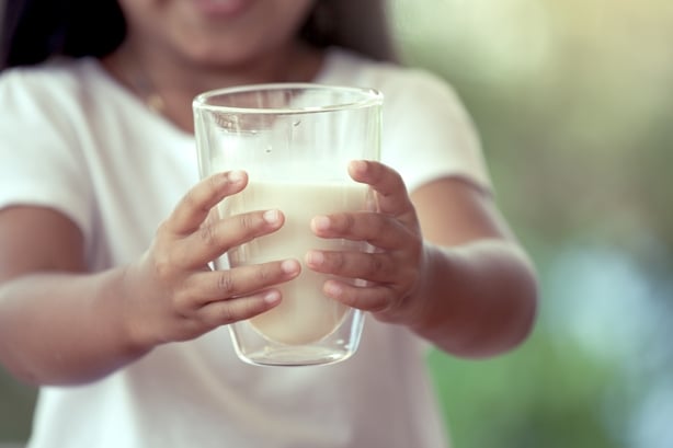 Closeup child hand holding a glass of milk
