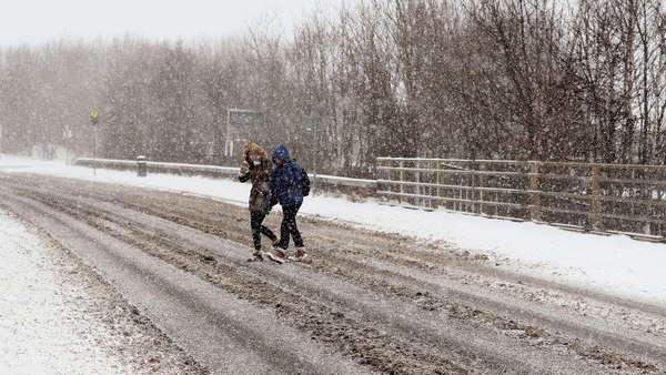 People cross a road as snow falls in Dublin