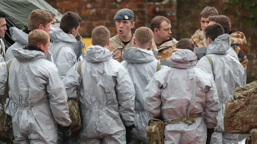 Military personnel in protective clothing prepare to remove vehicles from a car park in Salisbury, England, today