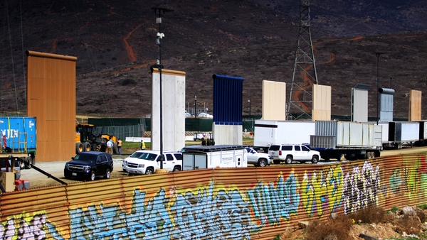 The prototypes tower over the existing graffiti-covered border fence near hills on the edge of San Diego