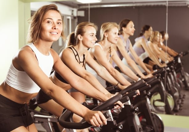 Girls during workout on stationary bicycle in fitness gym