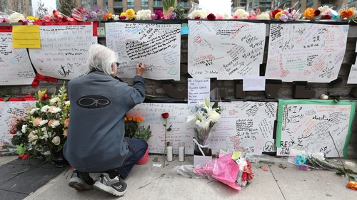 A man leaves a notes at a makeshift memorial for the victims in Toronto