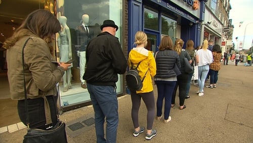 Customers queue up to take out cash at an ATM in Dublin today