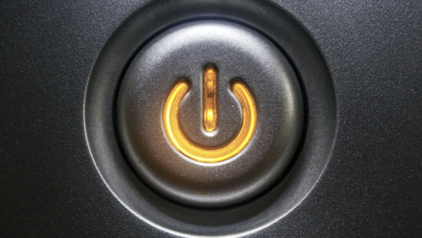 Extreme close-up of a black standby button glowing orange