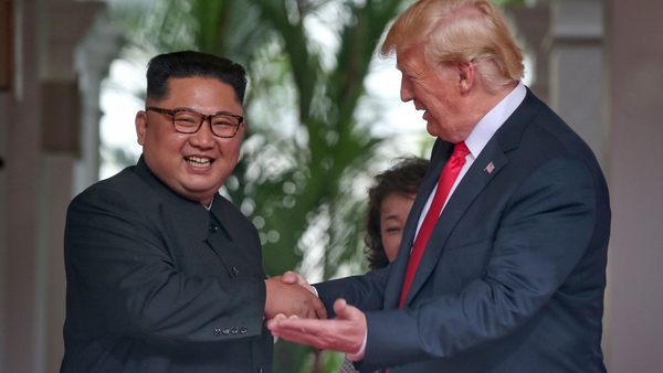 Kim Jong-un and Donald Trump smile after shaking hands at the start of their summit