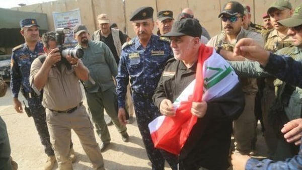 Haider al-Abadi, with a national flag on his shoulder, vowed to avenge the deaths of eight IS captives a day after their bodies were found