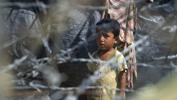 A child is seen behind a barbed wire fence in 'no man's land' at the border betweeen Myanmar and Bangladesh