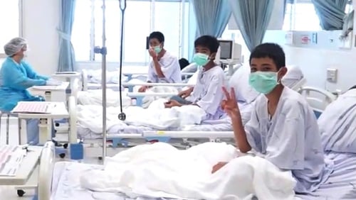 One of the boys gives a victory sign from his hospital bed