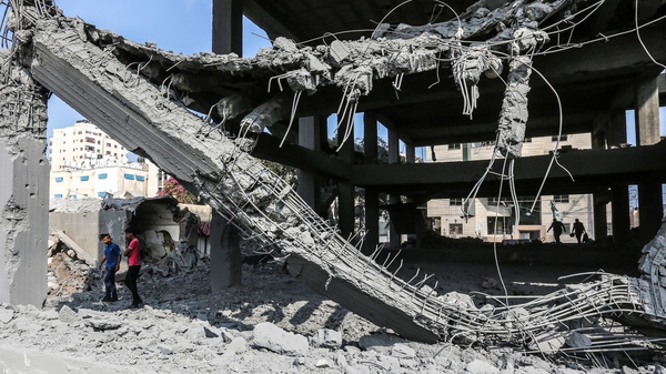 Palestinians walk among the wreckage of a building in Gaza following Israeli air strikes