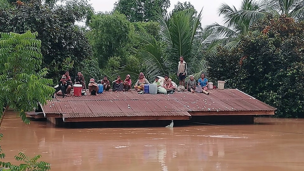People stranded on the roof of their home wait to be rescued