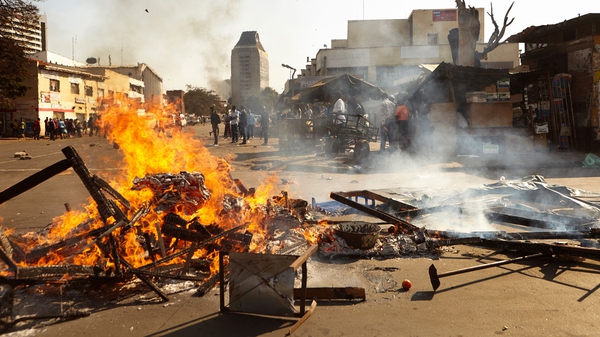 The wreckage of a market stall burns in Harare after protests erupted over alleged fraud in the country's elections
