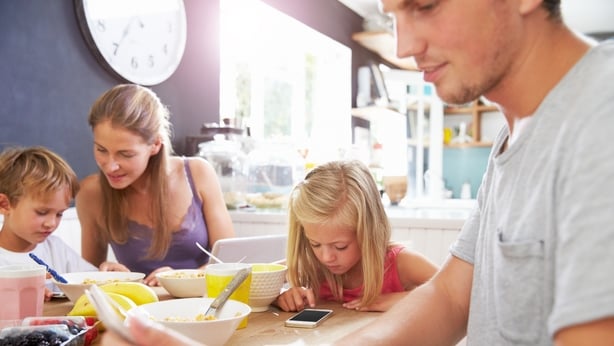 A family all using digital devices at the breakfast table