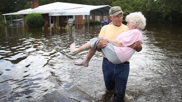 A woman is carried from her home in Spring Lake, North Carolina, as flood waters seep inside