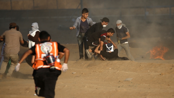 Palestinians medics help a protester near the border