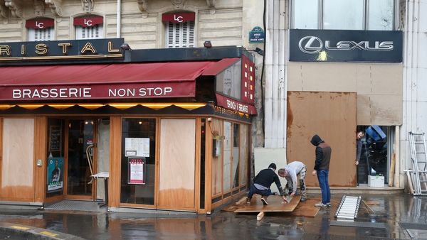 Workers install wood panels to protect the windows of a restaurant in Paris against possible damage